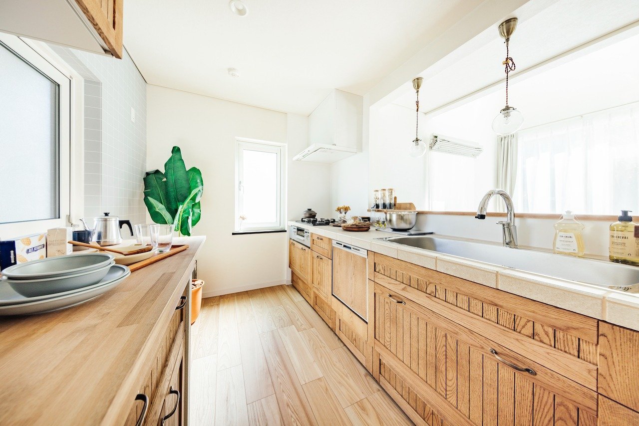 白いタイル貼りのキッチン。木の面材とタイルがナチュラル空間